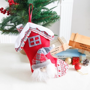 Kerstsok met kabouter en huisdak ontwerp hangend aan een feestelijke boomtak