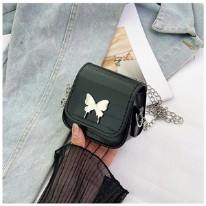 Detalle de un mini bolso bandolera acolchado negro con hebilla de mariposa plateada