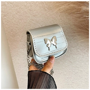 Detalle del mini bolso silla plateado con cierre de lazo metálico y piel con textura