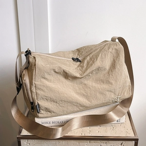 Sac bandoulière en nylon kaki avec large sangle sur un fond au design minimaliste