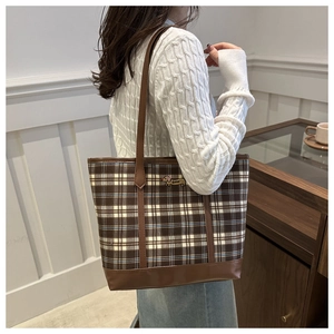 Detail of checkered canvas tote bag with dog embroidery worn over the shoulder