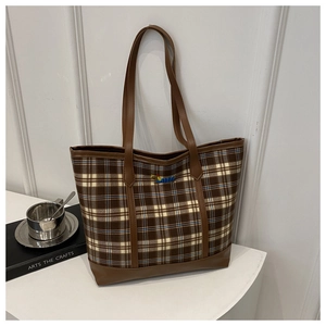 Detail of vintage plaid canvas tote bag with embroidered caterpillar and leather strap