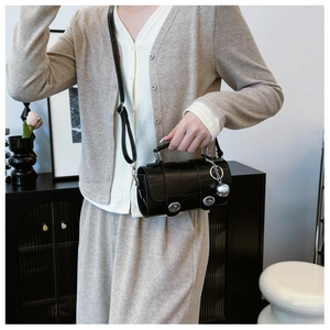 Detail of black eel texture cylinder bag with silver twist lock and metal ball charm