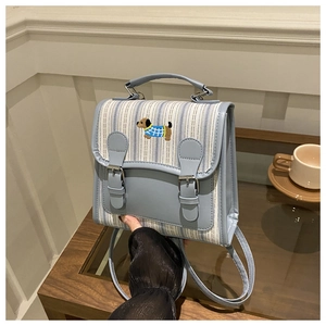 Close-up of light blue striped backpack featuring detailed dachshund embroidery