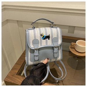 Detail of light blue striped backpack with dog embroidery and vintage strap buckles