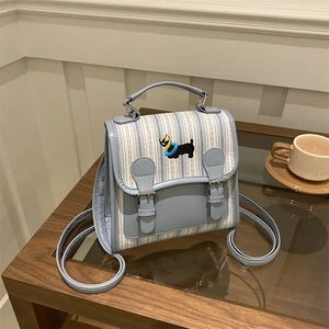 Mini backpack in blue striped fabric with dog embroidery and silver buckle on wood table