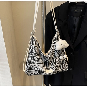Detail of knit tote bag with black and white geometric pattern and cloud charm