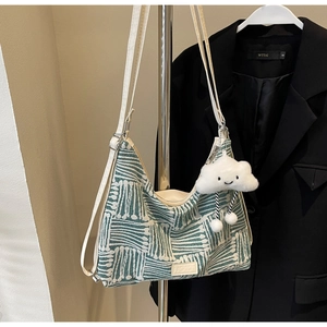 Detail of green wavy knit tote bag with adjustable strap and plush cloud pendant
