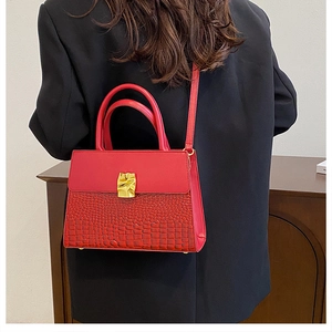 Detailed back view of model wearing a red crocodile embossed leather handbag with gold buckle