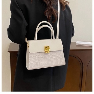 Detail of white crocodile-embossed leather handbag with elegant wavy gold metal buckle