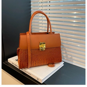 Detail of caramel crocodile pattern handbag with gold ripple buckle and smooth leather