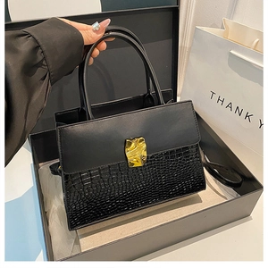 Detail of black crocodile texture handbag with gold buckle in premium gift box