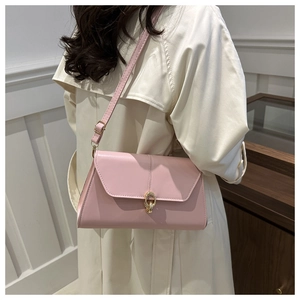 Close-up of elegant light pink shoulder bag with gold hardware worn by a model