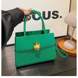Detail of green handbag with crocodile texture and artistic gold metal clasp on smooth leather