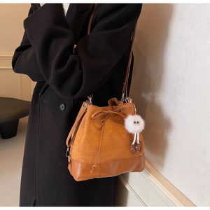 Brown vintage bucket bag with contrast leather trim and cute plush monster charm