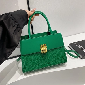 Chic green crocodile pattern handbag with gold clasp shown on a display stand