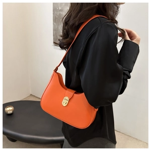 Chic orange crescent underarm bag with gold swivel lock shown on model shoulder