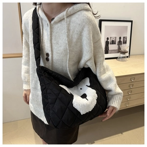 Close-up of quilted black hobo bag featuring a white plush puppy patch detail
