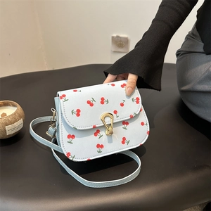 Light blue square crossbody bag with red cherry print and golden metal clasp closure