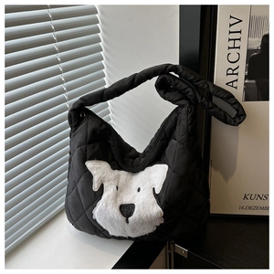 Detail of black quilted shoulder bag featuring a cute white plush dog patch design