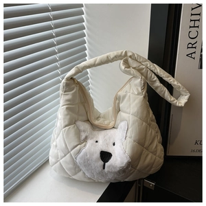 Detail of white quilted tote bag featuring a cute plush puppy patch and metal zipper