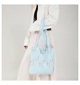 Detail of light blue canvas tote bag featuring colorful rainbow striped embroidery texture