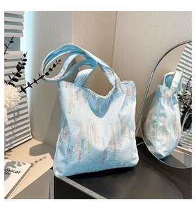 Close-up of light blue pleated tote bag with vertical rainbow embroidery and wide straps