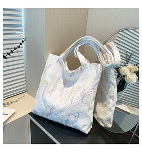 Detail showing colorful stripe embroidery and textured jacquard fabric on the white tote bag