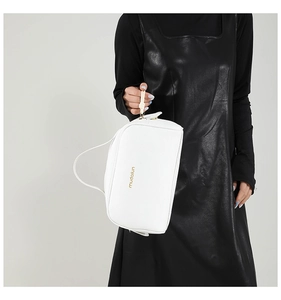 Close-up of white lychee pattern leather tote bag with gold logo and top zipper detail