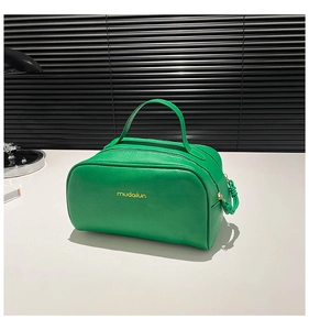 Détail du sac à main vert en cuir grainé avec fermeture éclair dorée et pendentif