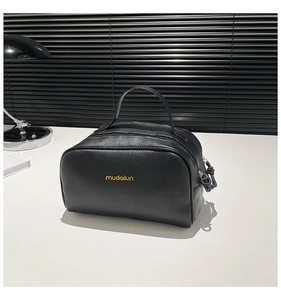 Détail du sac de voyage en cuir grainé noir avec double fermeture éclair et logo mudailun