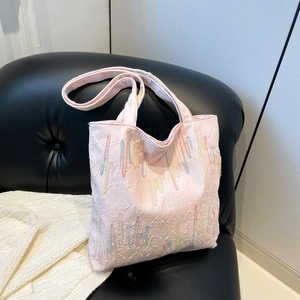 Pink tote bag with colorful embroidered waves and jacquard logo pattern on leather sofa