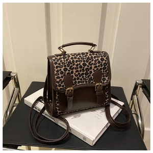 Detail of leopard print flap and gold clasp on a brown faux leather crossbody bag