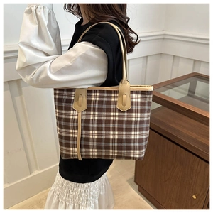 Close-up of a large plaid tote bag in brown and beige worn by a model for commuting
