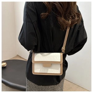 Crossbody view of a contrast-color small flap bag with crocodile embossed texture