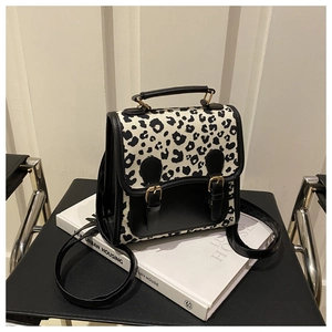 Detailed view of leopard print backpack with gold buckles on white fashion books