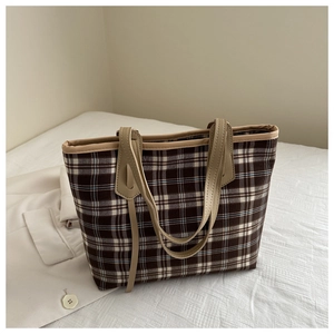 Detailed view of checkered tote bag with leather straps and blue brown plaid pattern