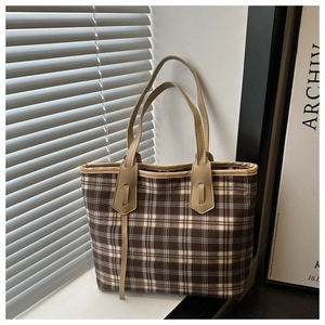 Detail of checkered canvas tote bag with brown leather straps in a minimalist setting