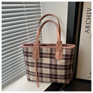 Detail of pink plaid tote bag featuring leather handles and decorative leather tassels