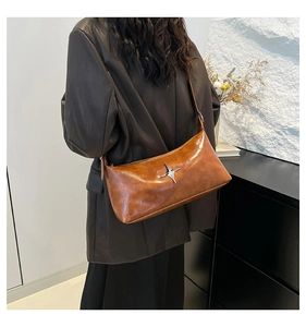Detailed view of brown faux leather shoulder bag with silver star metal accent on a model