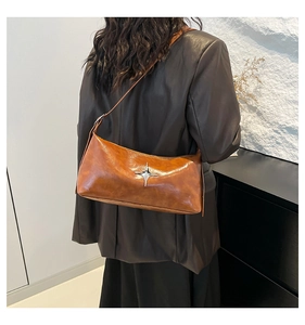Close-up of caramel brown pillow bag featuring a silver star metal accent on glossy leather