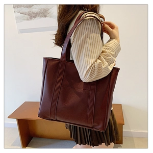 Detail view of burgundy PU leather tote bag with long straps and front pocket for daily use