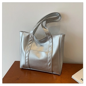 Close-up of metallic silver tote bag featuring pleated PU leather texture and front pocket