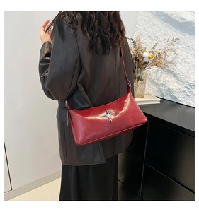 Detail of red glossy underarm bag with a silver star buckle and sleek rectangular shape