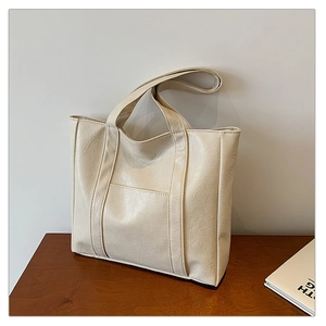 Detail shot of beige pleated PU leather tote bag featuring a front pocket and soft texture