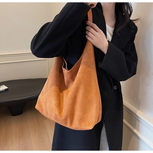 Detail of a large orange suede tote bag showing its soft texture and wide shoulder strap