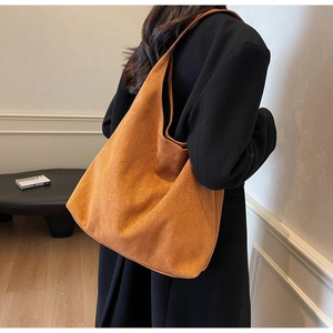 Detail of a large caramel suede tote bag with a soft texture and minimalist shoulder strap