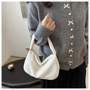 White corduroy baguette bag worn by model showing the ribbed texture and zipper detail