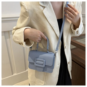 Gros plan d'un sac à main bleu clair en cuir PU avec boucle carrée sur blazer beige