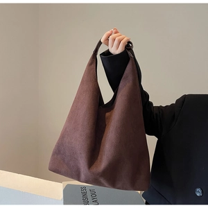 Detail of a dark brown suede hobo tote bag featuring a textured matte finish and large capacity